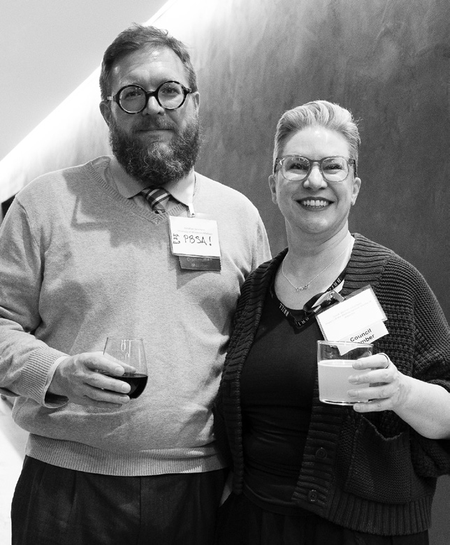 Journal editors smiling at the camera, both holding drinks and wearing name badges at the 2025 BSA Annual Meeting.