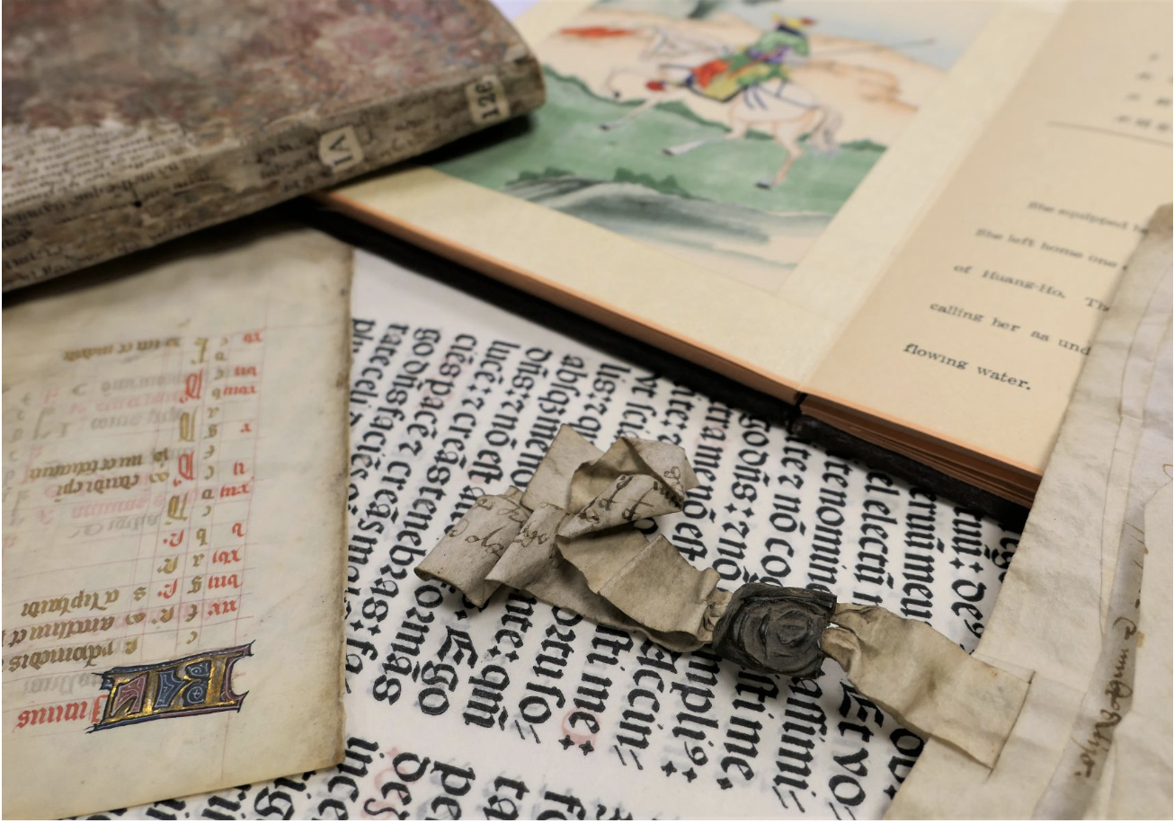 A collection of historical documents and books, featuring a manuscript with Gothic script and an open book showing a colorful illustration.