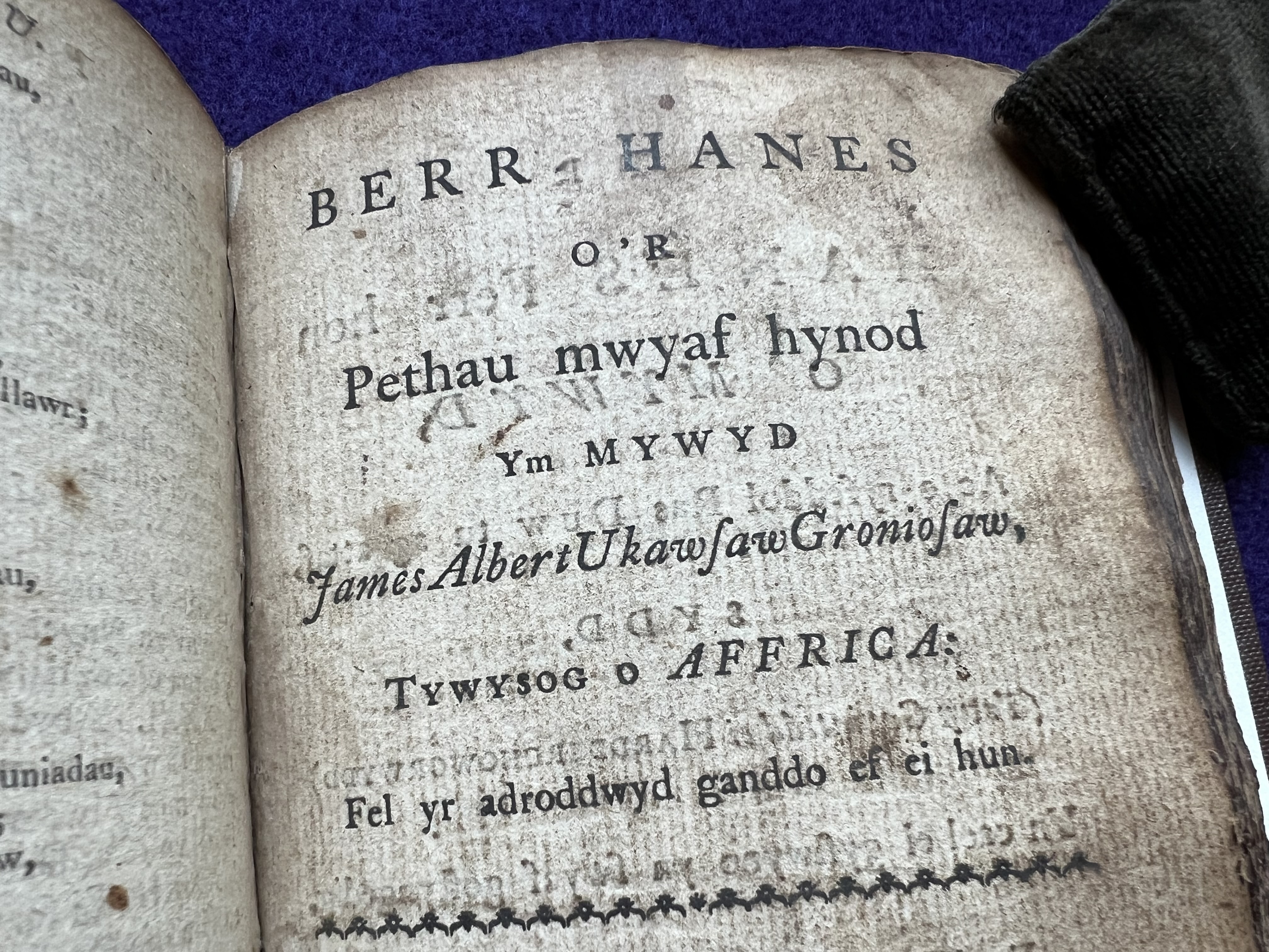 An open page of an old, worn book with Welsh text on aged, spotted paper.