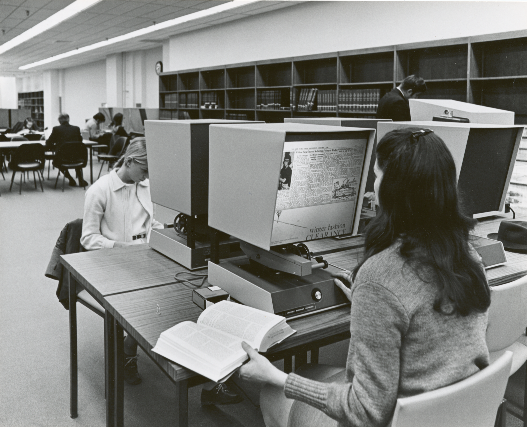 Two researchers seated at microfilm readers at the Mid-Manhattan Branch of the New York Public Library.